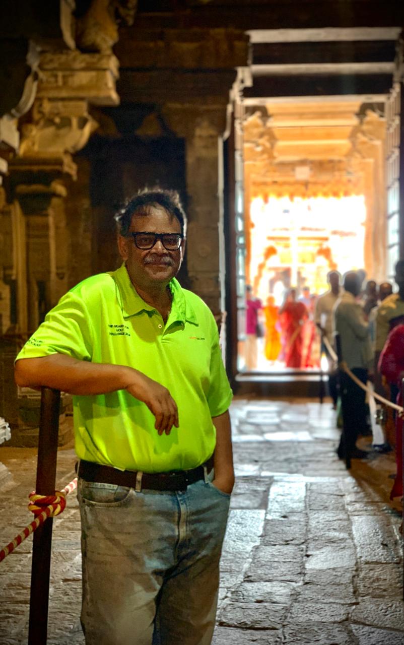 A dim stone temple corridor with carved columns, opening onto a brightly lit inner doorway where people queue